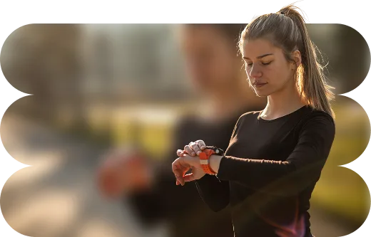 Κοπέλα με αθλητικά ρούχα κοιτάζει το smartwatch της.  