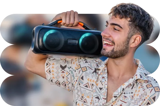 Νέος άνδρας γελάει και κρατάει ένα φορητό ηχείο.  